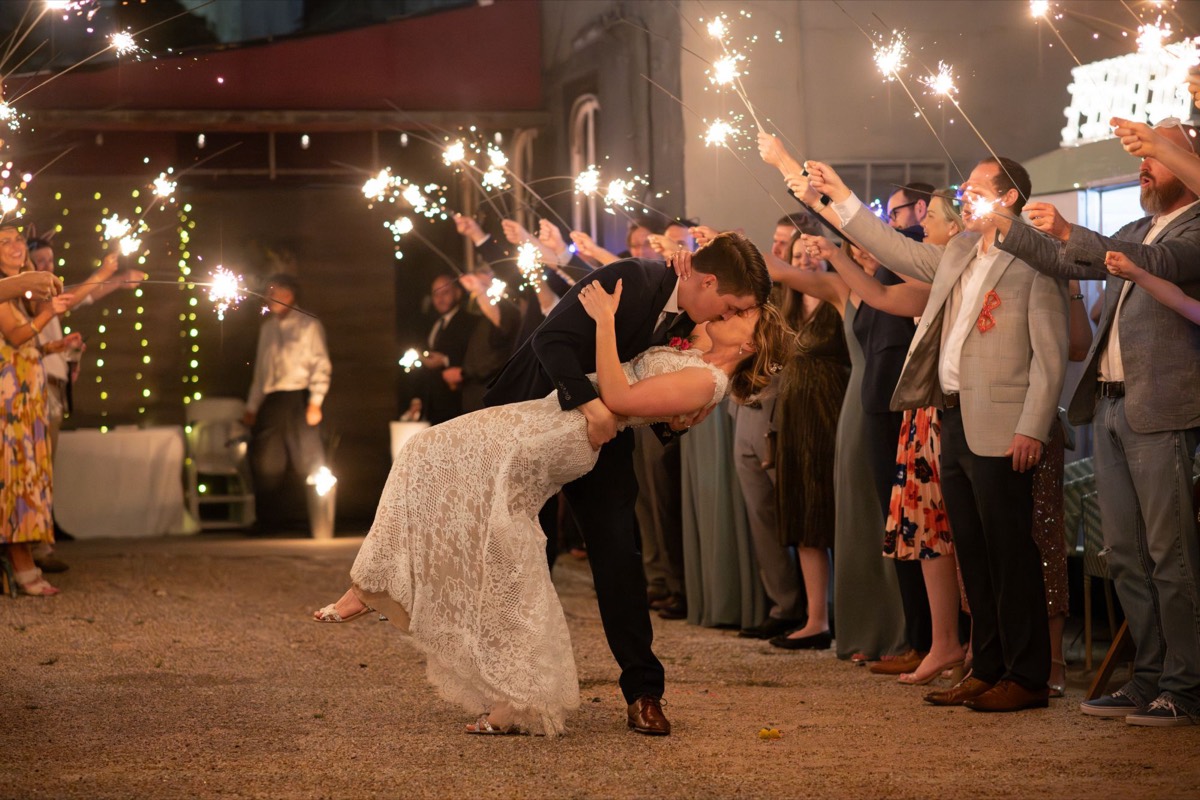 Bride and groom dip for a kiss during a sparkler exit at their Texas wedding